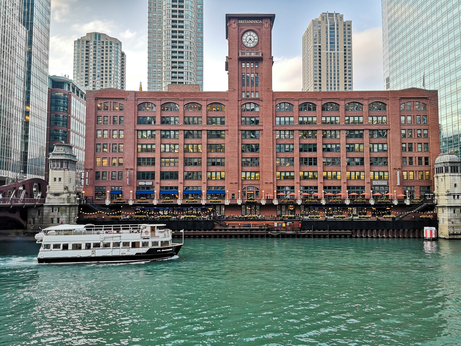 a boat traveling down a river past a tall building